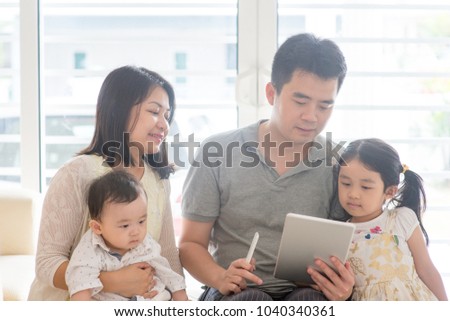Chinese adult scanning QR code with smart phone. Asian family at home, natural living lifestyle indoors.