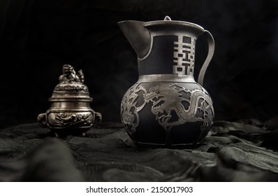 Chinese antique teapot (Characters chinese is Double Happiness) in frot of Silver antique incense burner on dark background. Chinese traditional style, Copy space, Selective focus. - Shutterstock ID 2150017903