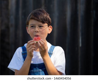Chinese Asian boy in coveralls eating watermelon