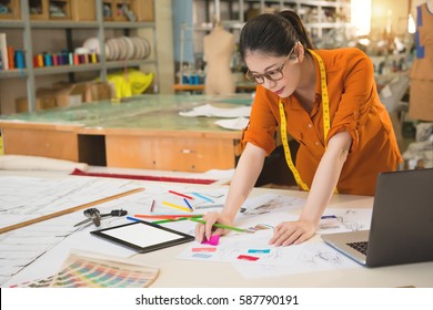 Chinese Asian design school  woman has ponytail thinks how to drawing with colorful pencil and ruler and scissors in studio  in manufacturing office studio. profession and job occupation concept - Powered by Shutterstock