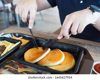 Chinese Asian Guy Who Wear Watch Is Using Plastic Knife And Fork And Cutting Pancake Breakfast Burger King Meal In Bangkok Thailand. February 12,2020