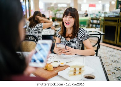 A Chinese Asian Lady Enjoys High Tea With A Good Friend At A Restaurant. She Is Beautiful, Elegant And Is Smiling As She Talks Animatedly With Her Friend Over Cakes And Tea On A Weekend.