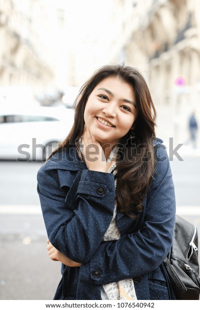 Chinese\
beautiful female tourist standing in road background in Europe.\
Concept of tourism and international\
students.