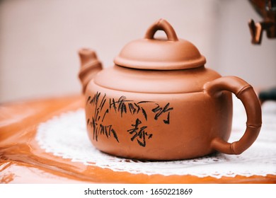 Chinese brown teapot and teacups on the wooden trivet isolated on white