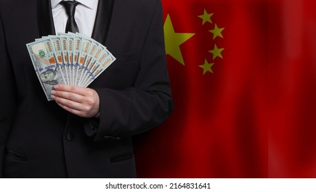 Chinese Business Man Showing 100 US Dollar Bills Against Flag Of China Background