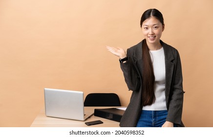 Chinese business woman in her workplace holding copyspace imaginary on the palm to insert an ad