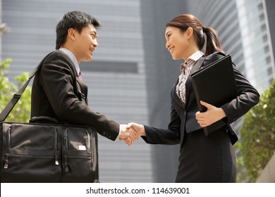 Chinese Businessman And Businesswoman Shaking Hands Outside Office