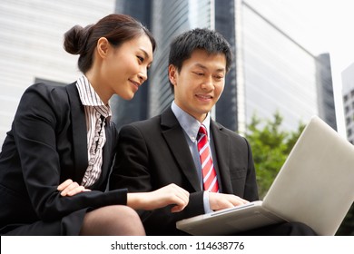 Chinese Businessman And Businesswoman Working On Laptop Outside Office