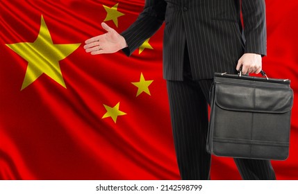 Chinese Businessman. Man Holds Out His Hand For Handshake. Concept Is A Business Partnership With China. Business With People Republic Of China. Business Cooperation At PRC. China Flag Behind Men