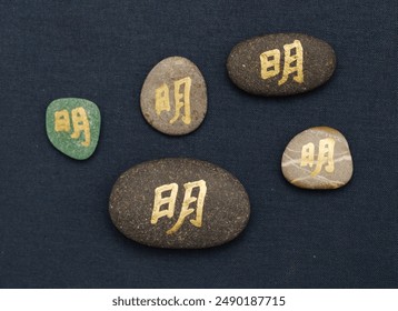 Chinese character ming or Japanese mei, meaning bright, written on a rock pebble - Powered by Shutterstock