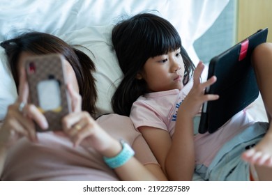 chinese child playing smartphone with mother, kid addicted tablet - Shutterstock ID 2192287589