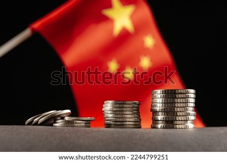Chinese coins with the flag of the People's Republic of China in the background. The concept of crisis in China. Close up
