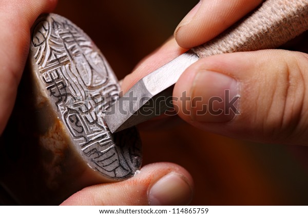 Chinese craftsman carving\
a stone seal
