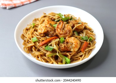 Chinese cuisine, Prawns Chilli garlic noodles. Stir fry noodles with vegetables and shrimp. served in a white plate. Hakka noodles With copy space.
