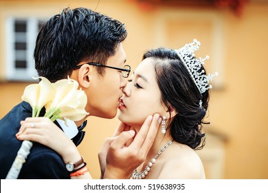 Chinese cute bride and groom young newlyweds just married couple kiss on streets of old city on wedding day