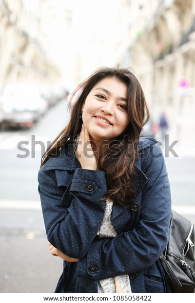 Chinese cute\
female tourist standing in road background in Europe. Concept of\
tourism and international\
students.