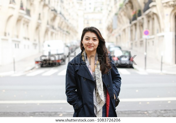 Chinese cute girl standing in street background,\
walking after classes. Concept of international students and\
strolling in city.