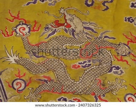 A Chinese dragon on Qing (1644-1911) emperor's robe made with bright yellow brocaded satin with eight auspicious patterns.