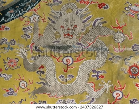 A Chinese dragon on Qing (1644-1911) emperor's robe made with bright yellow brocaded satin with eight auspicious patterns.