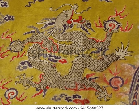 A Chinese dragon on Qing (1644-1911) emperor's robe made with bright yellow brocaded satin with eight auspicious patterns.