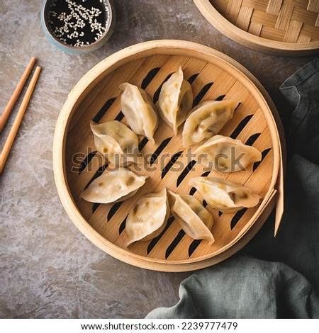 Chinese dumplings on a steamer, soy sauce and chopsticks. Traditional Chinese, Asian dish. Dim sum dumplings steamed in a steamer, square crop