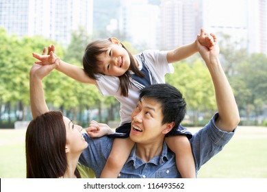 Chinese Family Giving Daughter Ride On Shoulders In Park