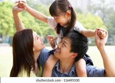 Chinese Family Giving Daughter Ride On Shoulders In Park