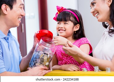 Chinese Family Saving Money For College Fund Of Child, Putting Coins In Jar