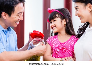 Chinese Family Saving Money For College Fund Of Child, Putting Coins In Jar