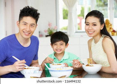 Chinese Family Sitting At Home Eating A Meal