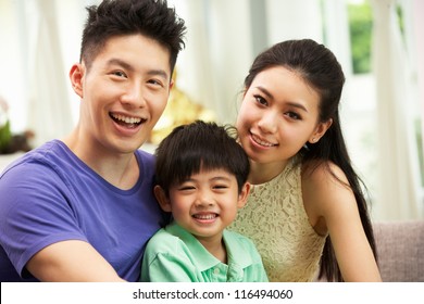 Chinese Family Sitting And Relaxing On Sofa Together At Home