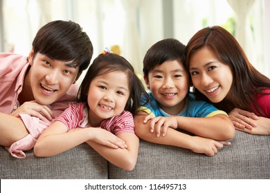 Chinese Family Sitting And Relaxing On Sofa Together At Home