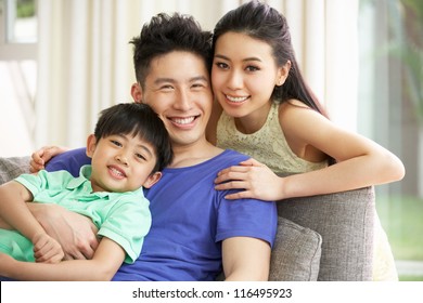 Chinese Family Sitting And Relaxing On Sofa Together At Home