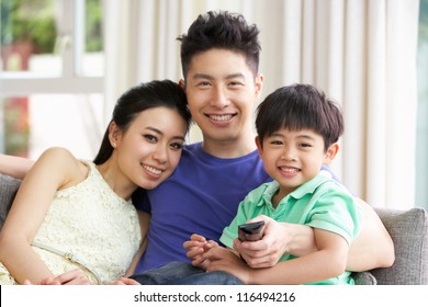 Chinese Family Sitting And Watching TV On Sofa Together