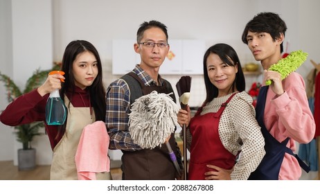 chinese father. mother. daughter and son standing up holding brooms and spray and looking at camera while posing in the kitchen at home. prepared for chinese lunar new year spring cleaning. - Shutterstock ID 2088267808