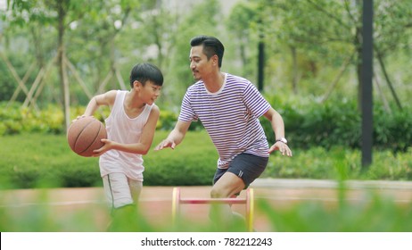 Chinese father & son playing basketball in garden in morning