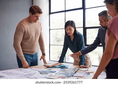 Chinese female architect discussing with multiethnic team while examining architectural plans and materials during a meeting. Casual architects and engineers discussing about building construction. - Powered by Shutterstock