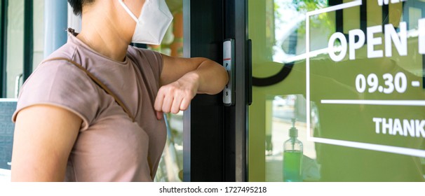 Chinese Female Wearing Medical Mask Using Elbow Press Automatic Doors Button To Open The Door Of Takeaway Restaurant. Social Distancing, Self Isolation Or New Normal Concepts