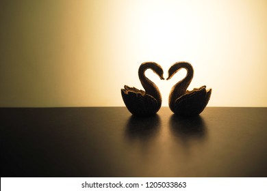 Chinese Feng Shui For Love. Couple Of Gold Swan Figurines In Dark Light For Romantic Theme.