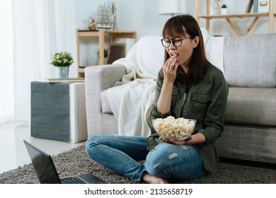 Chinese Girl Eating Snack Is Binge Watching On Her Notebook In Her Free Time. Cute Girl Is Enjoying Some Popcorn And Watching A Popular Drama Online Pleasantly.