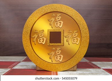 A Chinese Gold Coin With The Word Fortune Written On It