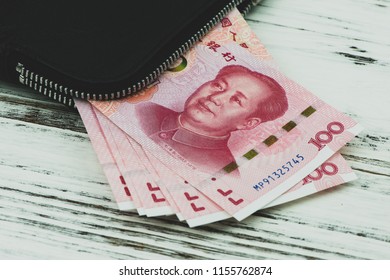 Chinese Hundred-dollar bills on top of a black wallet.