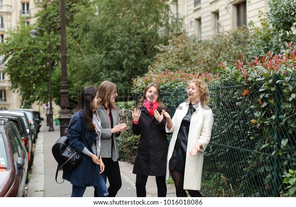 Chinese international student speaking\
with teacher outside in  . Concept of studying abroad and learning\
language. Young girls talking outside in\
coats.
