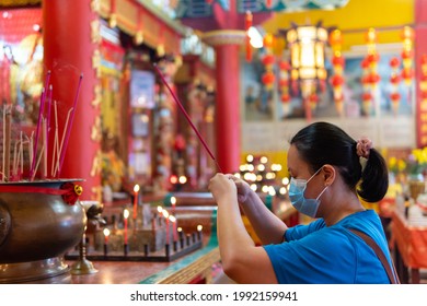 Chinese Lady With Medical Face Mask Pray With Holding Smoking Incense Sticks At Chinese Temple During Chinese New Year