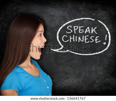 Chinese language learning concept. Woman speech bubble on blackboard saying SPEAK CHINESE. Fun happy mixed race student or teacher.