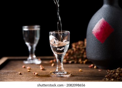 chinese liquor is pouring into a glass from a bottle on wood background	