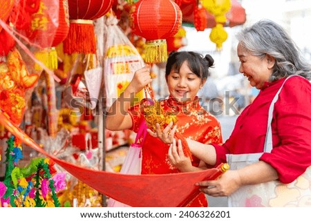 Chinese lunar new year festival and tradition holiday celebration concept. Asian grandmother and grandchild girl buying home decorative ornaments for celebrating Chinese New Year at Chinatown market.