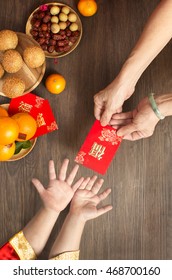 Chinese lunar new year flat lay traditional food and offering on table top. Senior women hands giving red packet to toddler boy hands. - Shutterstock ID 468700160
