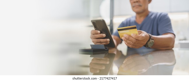 Chinese Man Holding Credit Card And Using Mobile Phone At Home, Asian Senior Male Making Online Shopping On Smartphone, Banner