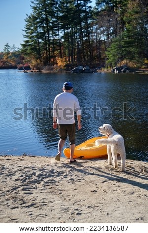 Chinese man and pet dog spending time together at a pond kayaking and hiking on a sunny fall day